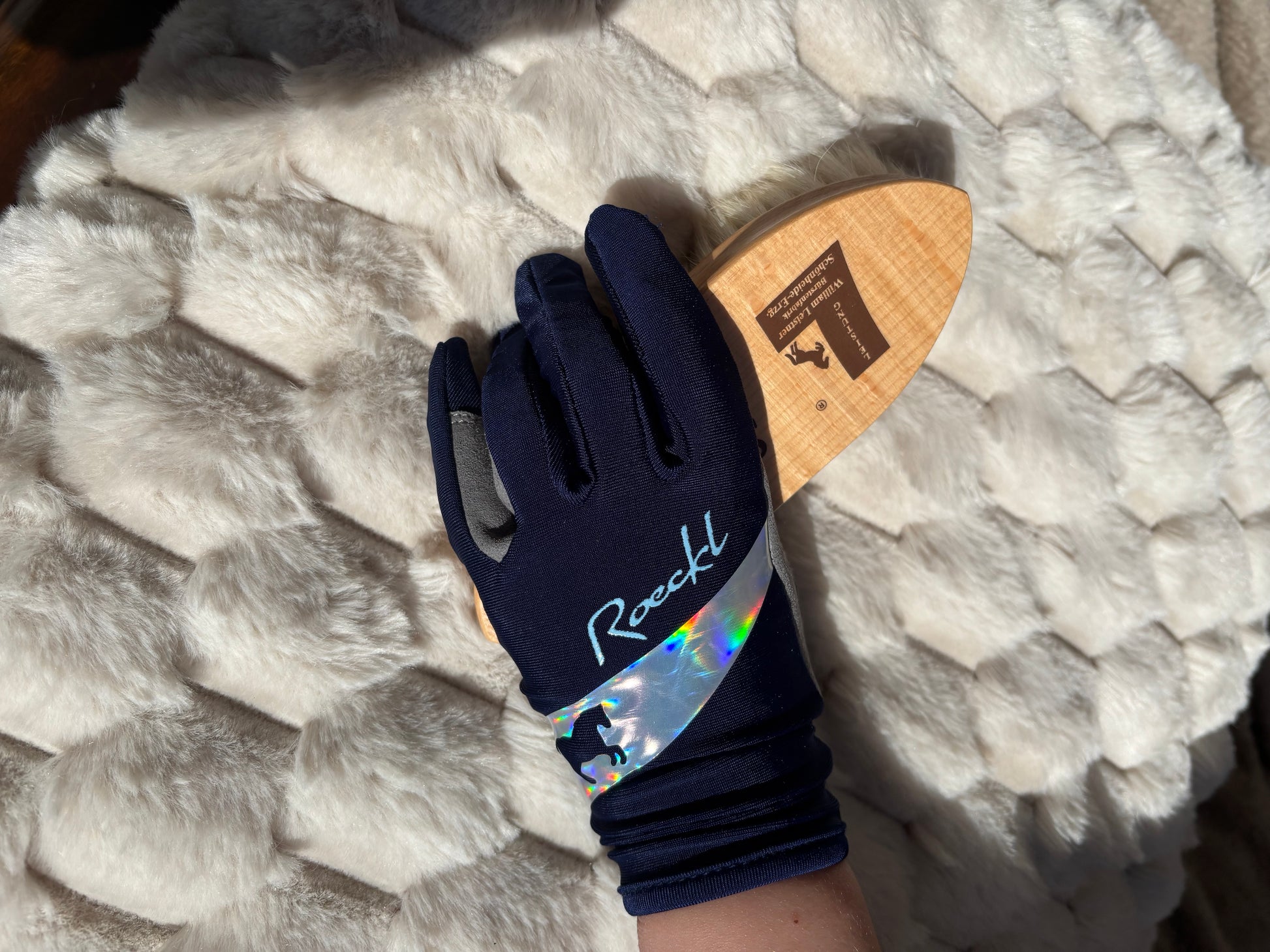 Marinblå barnridhandske från Roeckl i storlek 3.0-6.0 håller i Smoochy-borsten från William Leistner